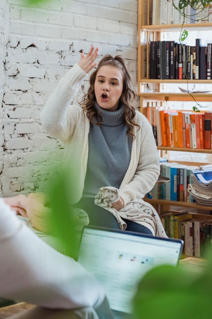 Annoyed woman emotionally shouting at husband and proving opinion to partner while man browsing laptop and ignoring