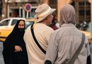 Back view of pedestrians walking on city sidewalk, showcasing diverse attire and urban life.