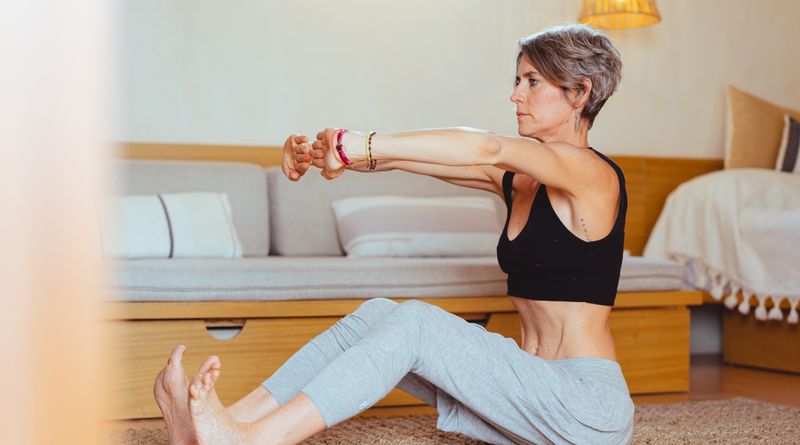 Elderly woman in a yoga pose indoors, embracing healthy lifestyle and wellness.
