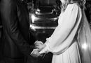 Intimate black and white wedding moment with bride and groom sharing vows under twinkling lights.