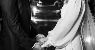 Intimate black and white wedding moment with bride and groom sharing vows under twinkling lights.