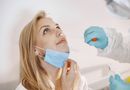 Medical professional performing a COVID-19 nasal swab test on a patient wearing a face mask.