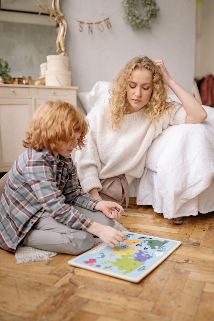 Mother and son bonding over a colorful world map puzzle indoors.