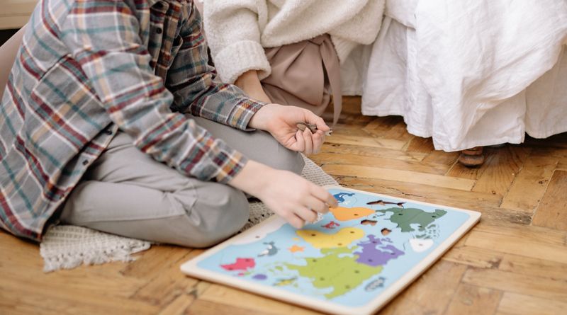 Mother and son bonding over a colorful world map puzzle indoors.