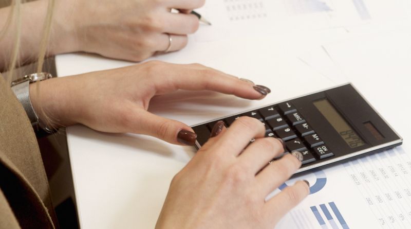 Team working with a calculator and reports on a professional desk.