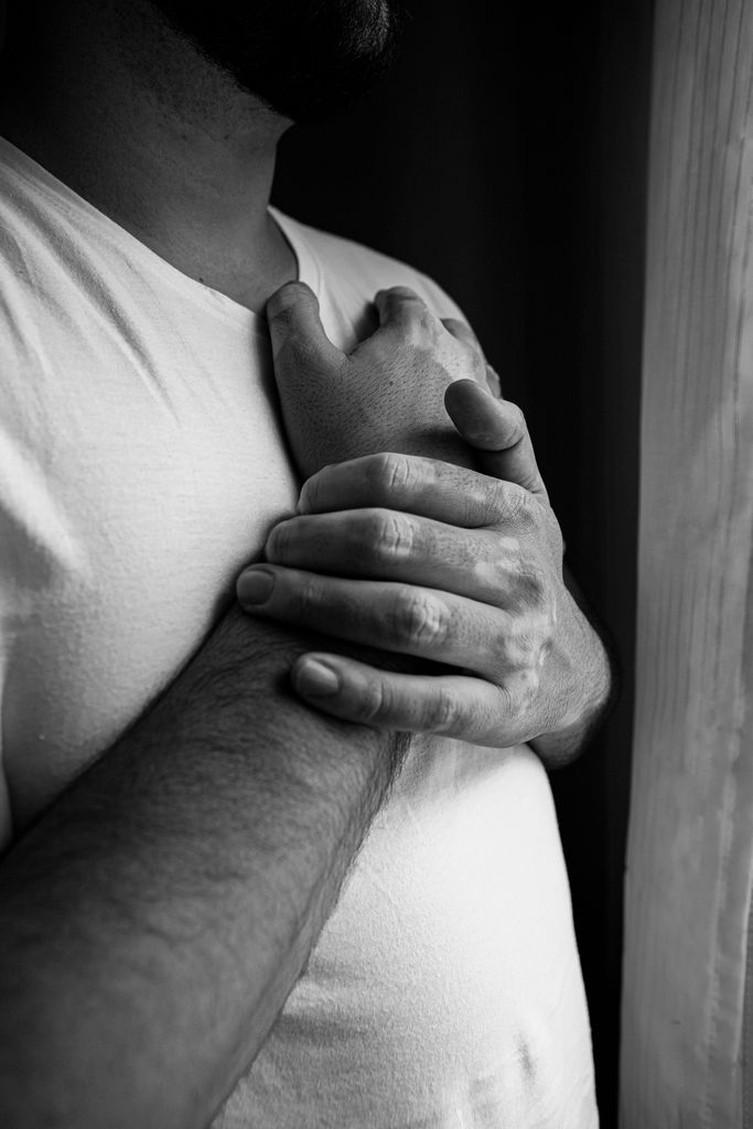 A black and white photo highlighting hands with vitiligo and a heart gesture, emphasizing emotion and diversity.