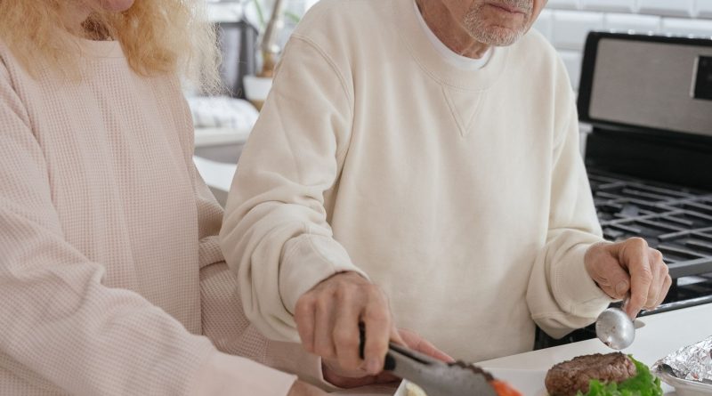 Elderly couple preparing burgers together in a contemporary kitchen setting.
