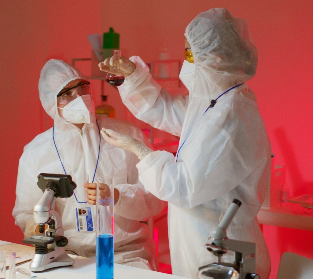 Two scientists in protective suits conduct experiments in a modern laboratory with microscopes and glassware.
